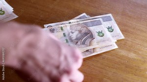 Man counts money, cash Polish zloty, close-up 200 PLN, money on the table