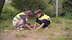 forest kindergarten. Happy Preschool group of children play in the swamp in park or forest. Outdoors small child have fun playing with mud in a woods. Hike. Summer Camp curious, leisure in nature