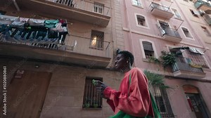 Young African American woman uses smartphone to send audio message,utilizing AI voice assistance,exploring Barcelona’s historic old town.Casual female tourist walk, backdrop of Mediterranean balconies