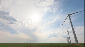 timelapse landscape of modern wind turbines in open field. the blades spinning in bright blue sky, fluffy clouds, summer. wind moves turbines symbolize renewable energy, environmental sustainability