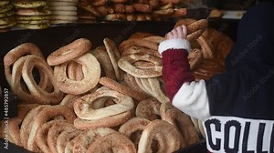 Traditional fresh jewish bread lies on open stall of market. Somebody hand's choice and takes bread. Bread make different form and lies as mountain. Close-up