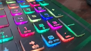 A gaming keyboard that has colorful LED lights, with the main color of the keyboard being black. It has a shape that is very suitable for the hand when typing or playing games.