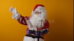 Santa Claus plays on a drum set.