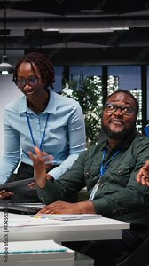 Vertical Video African american analysts collaborating on a project with financial forecasting, projecting data to expand the enterprise activity and profit. Teamwork in workspace to ensure objectives