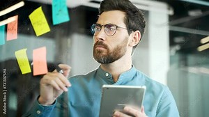 Creative business man in office uses post papers sticky notes to share idea. brainstorming, Thinking concentrated entrepreneur solving strategy. Using glass note wall board. Startup posted. Close up