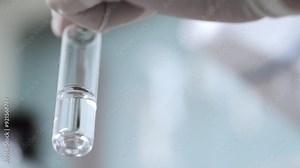 Scientist hand holding test tube with liquid sample during laboratory analysis.