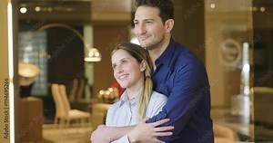 A couple of lovers in front of the window hug each other and look out as if looking at their future. Concept of: love, marriage, future, children and family.