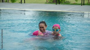 Little girl plays in the outdoor swimming pool of tropical resort during family summer vacation. Kids learning to swim. Healthy Summer Activities for Kids.