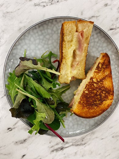CROQUE-MONSIEUR CROUSTILLANT À LA POÊLE INGRÉDIENTS POUR 4 PERSONNES 16 tranches de pain de mie frais 100 g de jambon blanc ou de dinde en fines tranches 200 g d’emmental ou parmesan ou gruyère râpé 1 œuf 100 g de crème fraiche Muscade (ou cumin en poudre) 100 g de beurre fondu 1 botte de ciboulette 1 salade Sel fin et poivre du moulin Si elles ne sont pas taillées, couper les tranches de pain de mie afin qu’elles aient toutes la même taille. Ciseler de la ciboulette. Dans un robot ou un bol de 