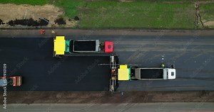 Laying new asphalt top view. Aerial view of road works, asphalt paver is laying a new layer of asphalt. Road construction equipment. Rollers rolling fresh hot asphalt on the new road.