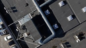 Top-down view of a rooftop featuring parking spaces, ventilation ducts, and HVAC units on a commercial building.