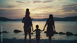 Happy family by the ocean together at sunset. children and parents walk along the beach as a team.
