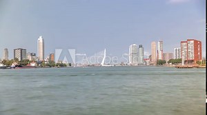 Erasmus Bridge timelapse panorama, called The Swan, spanning the Maas River in Rotterdam, Netherlands. Holland's largest cable-stayed bascule bridge with skyscrapers, boats and a cloudy blue sky