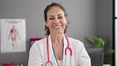 Middle age hispanic woman doctor smiling confident standing at clinic