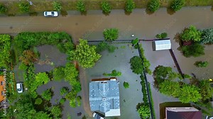 Drone aerial bird's-eye view of residential housing backyard home rooftops with cars parked in driveway fence property community living suburbs town neighbourhood trees