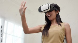 Young asian woman put on vr glasses into virtual simulated world metaverse. Future technology digital cyber universe. Person Enjoying an Experiences of Metaverse Virtual World.