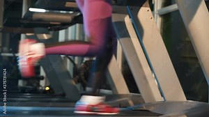 Woman in purple leggings is running on a modern treadmill in fitness club. Running legs in sneakers on simulator in gym. Cardio training. Close-up. Sport for slender figure.