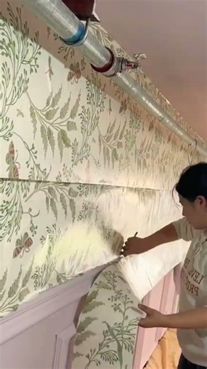 the process of installing floral patterned wallpaper on the walls in a room in a house #construction