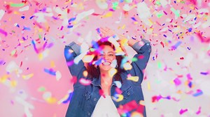 A young beautiful happy model strikes poses over a pink vibrant background with multicolored confetti descends on the scene in slow and fast motion - Free Stock Video