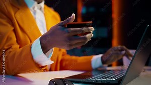 African american girl doing online shopping session at home, typing debit card numbers to finish website order. Young woman purchasing clothes with easy pay e banking, home delivery. Camera B.
