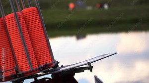Slow motion view of throwing machine for clay pigeon shooting with orange plates near water