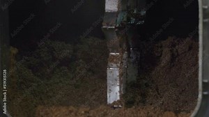 Close-up of huge amounts of spent grain inside of the tank container. Mixing the spent grain collected in the container. Mechanism stirring the spent grain in the container. Brewery facility.