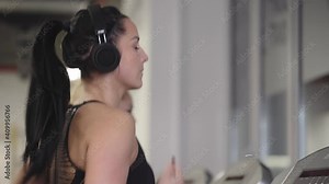 Fitness woman running on treadmill in gym. Athlete woman using run machine in fitness center.