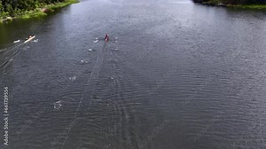 Drone footage of three athletes participating in a sculling race on a sunny day