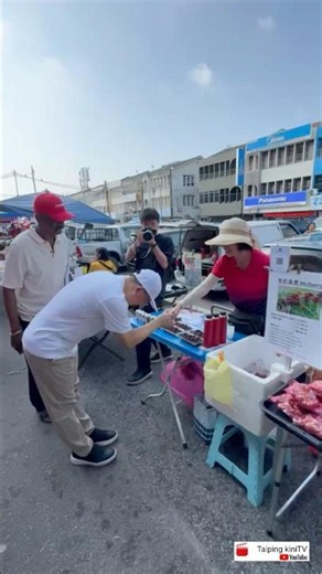 Nga Kor Ming visits the market to engage with the public, shaking hands and listening closely to ...