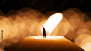 Dramatic Fluttering Candle Flame. A large candle close up against the background of a set of blurry lights. Filmed at a speed of 120fps
