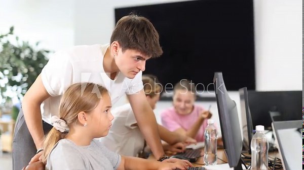 Concerned preteen girl sitting at computer while trainer explaining him something during IT courses