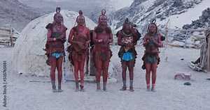 4K view of Himba woman in traditional dress dancing and singing outside their clay hut, Namibia