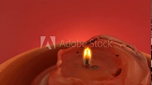 Red candle with yellow flame lit and blown out with smoke against red background in slow motion