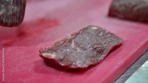 4k: Chef cutting raw meat on a cutting board in a professional kitchen. Closeup of chef slicing meat in slow motion.