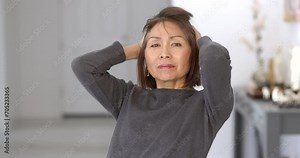 Portrait attractive woman relaxing looking at camera running fingers through hair folding arms smiling enjoying sitting at home.