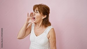 Furious middle age woman in pink dress, angrily yelling off to the side, shouting out her frustrations loud. amplifying her voice in communication over an isolated backdrop.