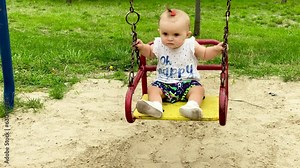 baby swinging on a swing on a clear summer day. Playground in the park