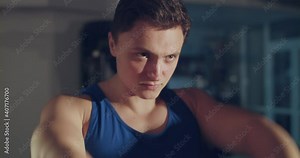 Young athlete in blue singlet doing circular movements of arms in a gym