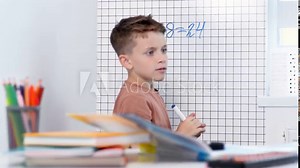 Rear view of young boy solving math problems on white board.