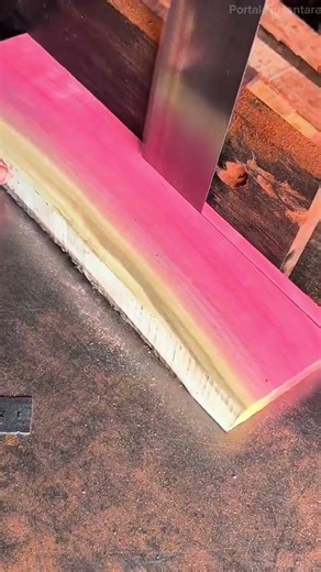 cutting a bright pink piece of wood using a large hand saw in a carpentry workshop setting