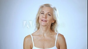 Happy smiling attractive 50s, 60s, middle aged mature woman looking at camera on white background. Anti age face beauty, skin and body care, wellness and self care concept. Close up portrait.