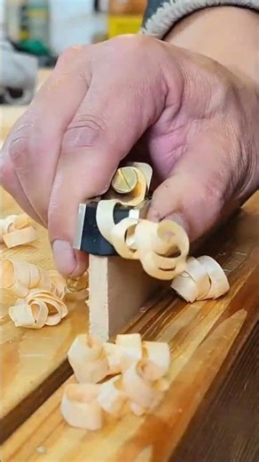 Smoothing out a wooden board edge using a traditional manual hand plane tool with precision