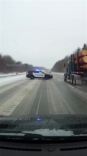 Interstate 15, Utah - December 21, 2025: A harrowing highway collision was captured on a commuter's dashcam during a heavy winter storm. A police cruiser responding to a separate incident lost traction on a patch of black ice, spinning across several lanes before being broadsided by a fully loaded logging truck. The momentum of the heavy load caused the trailer's rear axle to fail, sending logs tumbling onto the slick roadway. Miraculously, both drivers survived the incident with only minor inju
