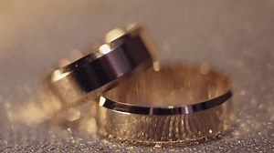 Wedding gols rings lying on shiny glossy surface. Shining with light. Close-up