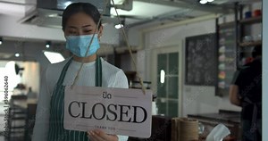Cafe or restaurant and business reopen after Coronavirus quarantine is over. Woman with face mask turning a sign from closed to open on a door shop. Small food shop business after post covid lockdown.