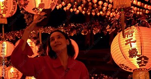Woman taking photos of many Chinese Lanterns at shrine. blessing text on lanterns meaning have wealth and happiness