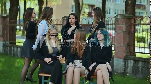 High school students having fun together, goofing around on a bench in the schoolyard during a break