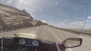 View from the front of a motorcycle going up a mountain, with view down opening to the right