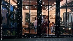 Cute little girl look through the window feel exciting to see snowfall first time of winter season. Adorable child sitting in a beautifully decorated living room in christmas festival with family.