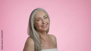 Happy aging. Portrait of positive beautiful senior grey haired lady with bare shoulders laughing over pink background